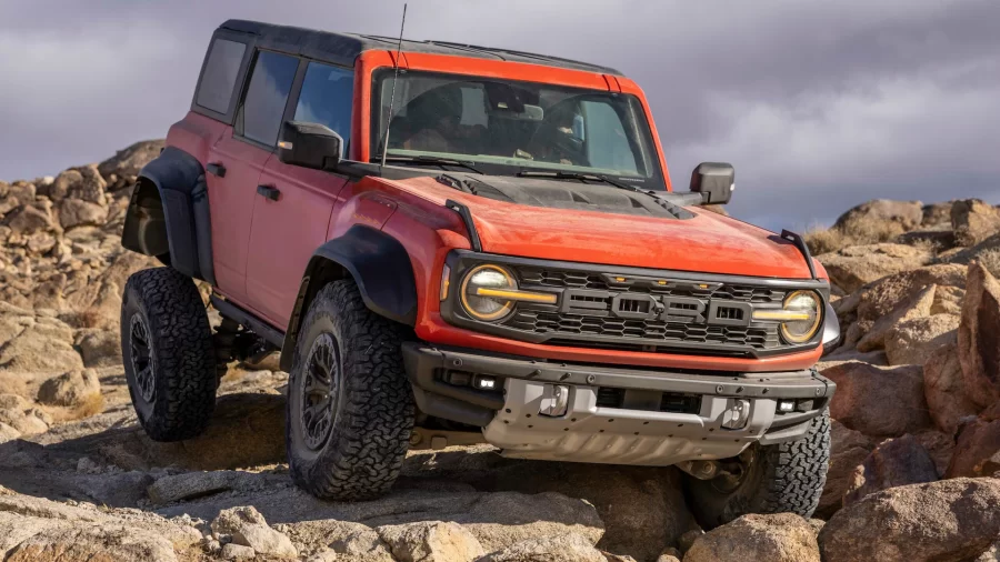 A+red+Ford+Bronco+Raptor+crawling+over+a+rugged+terrain.+%28Ford%29
