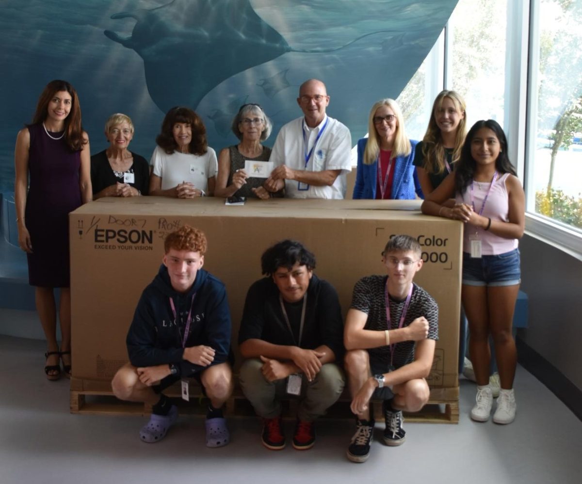Mr. Eder, members of MIFA,  Miss Scott, and students pose with the boxed printer after its arrival. 