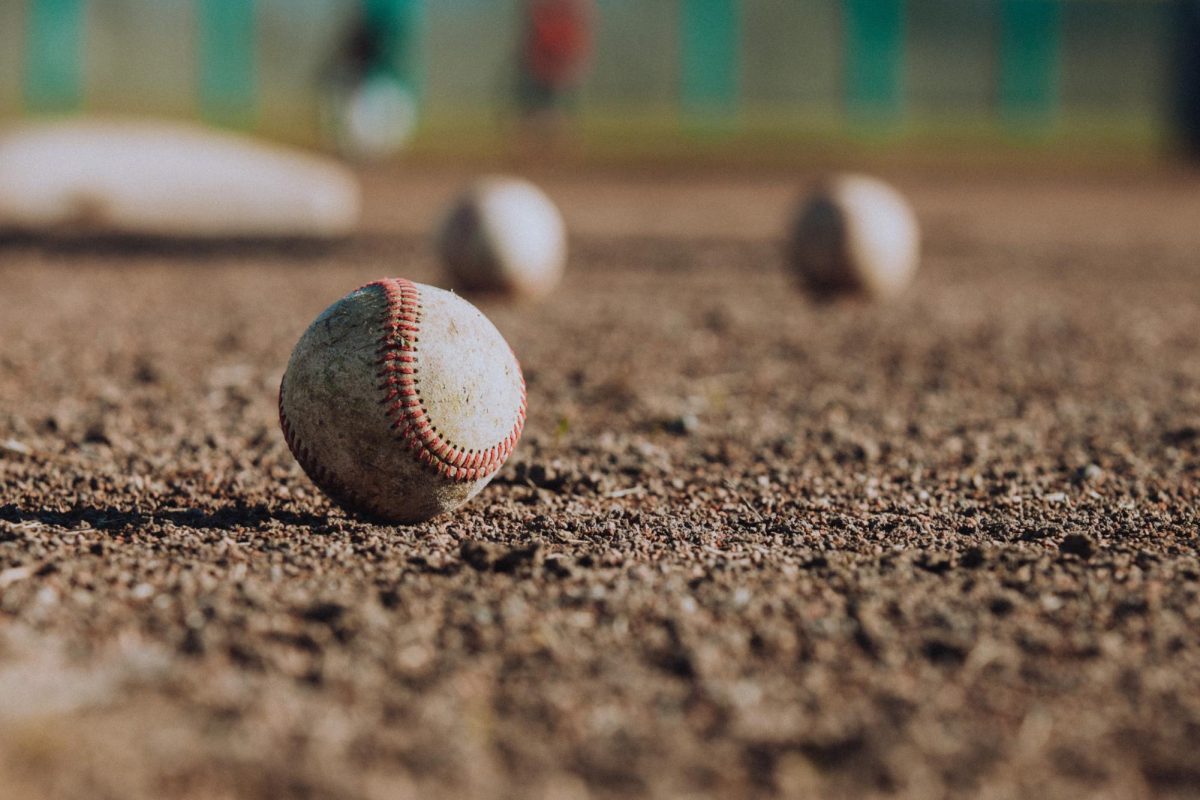 [Unsplash] This photo depicts a baseball resting on a dirt field.