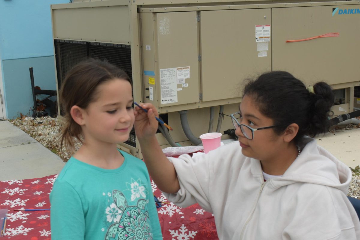 Senior, Nicole Garcia-Pantoja painting a little girl's face for Santa's Arrival.  