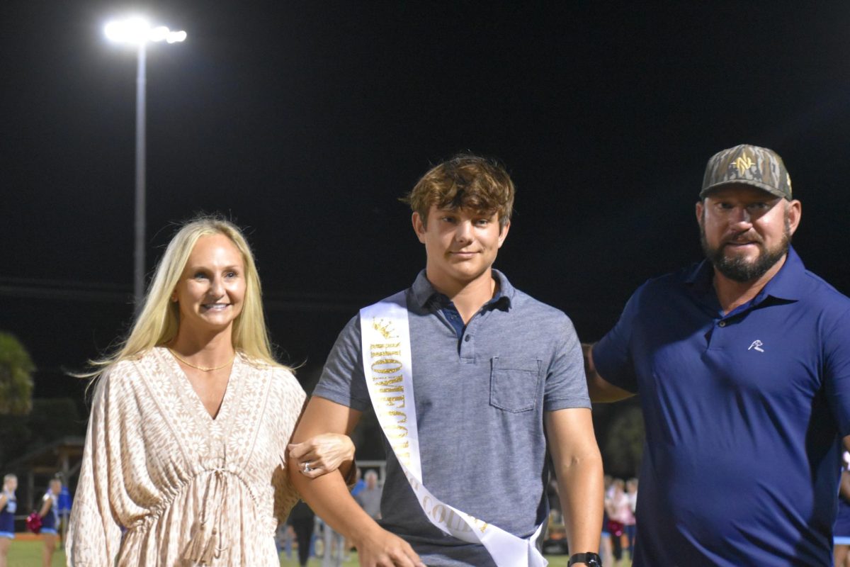 Senior homecoming court, Chase Polley being accompanied by his parents. 