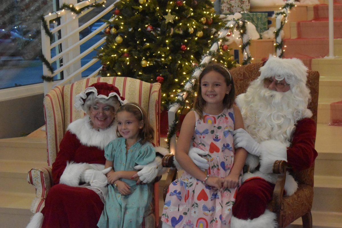 Two little girls posing happily with Santa and Mrs. Claus. 