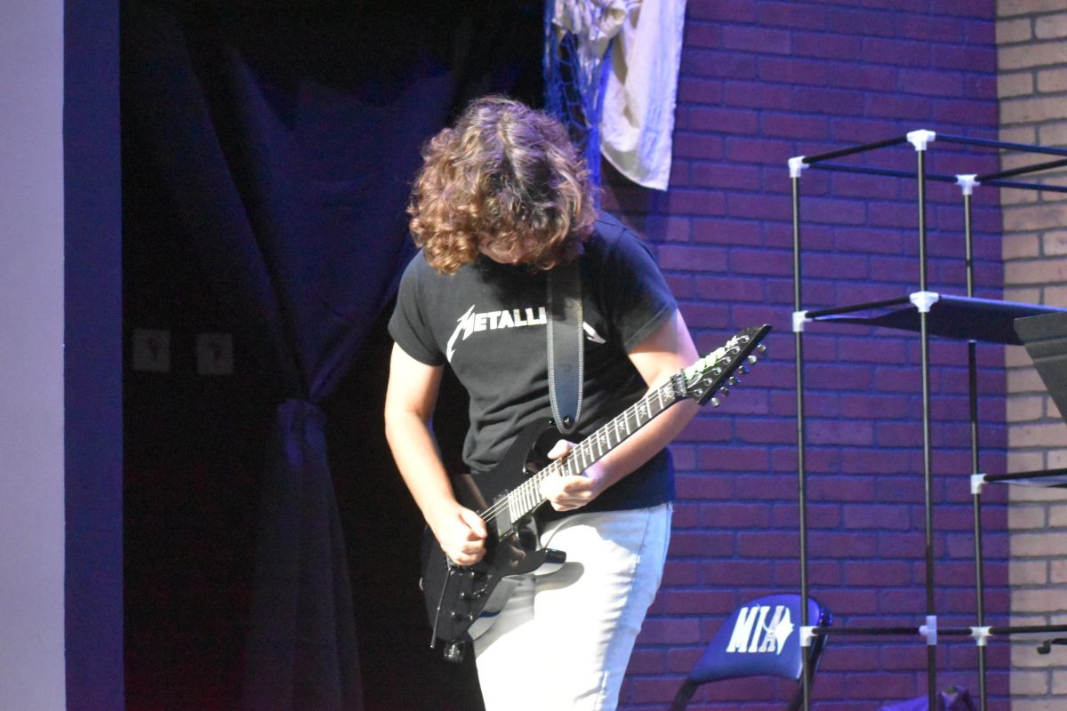 MIA student, Nathan S. playing the electric guitar with The Academy of Rock. 