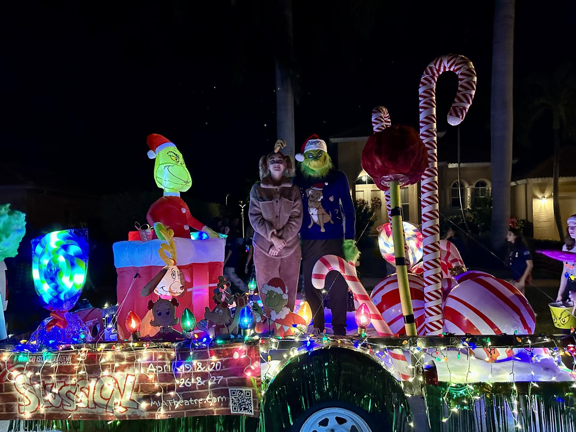 Photo credit to Janet Ferro. The Grinch and Max stand on the Whoville-themed float adorned with lights and colorful decorations.