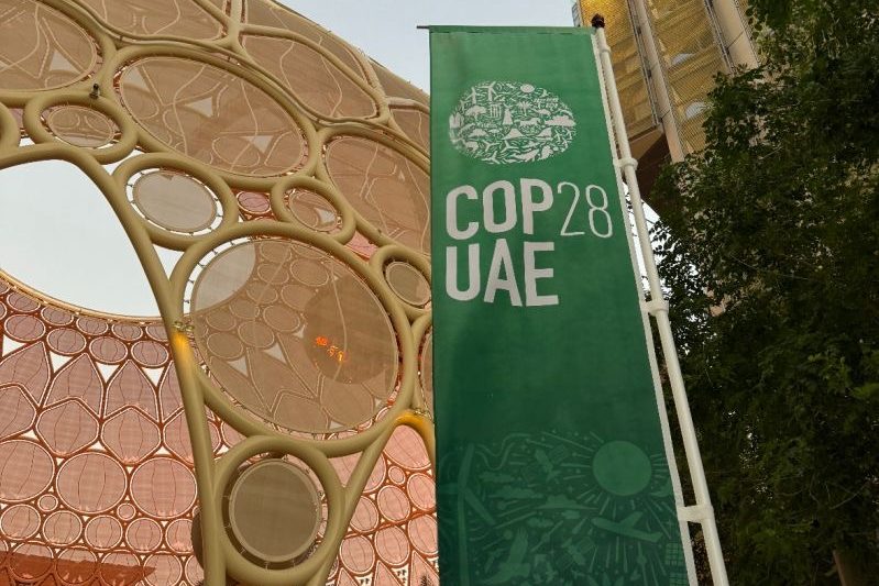 Photo credit to Anna Davis. A banner located at COP28 surrounded by the grandiose architecture of Dubai.