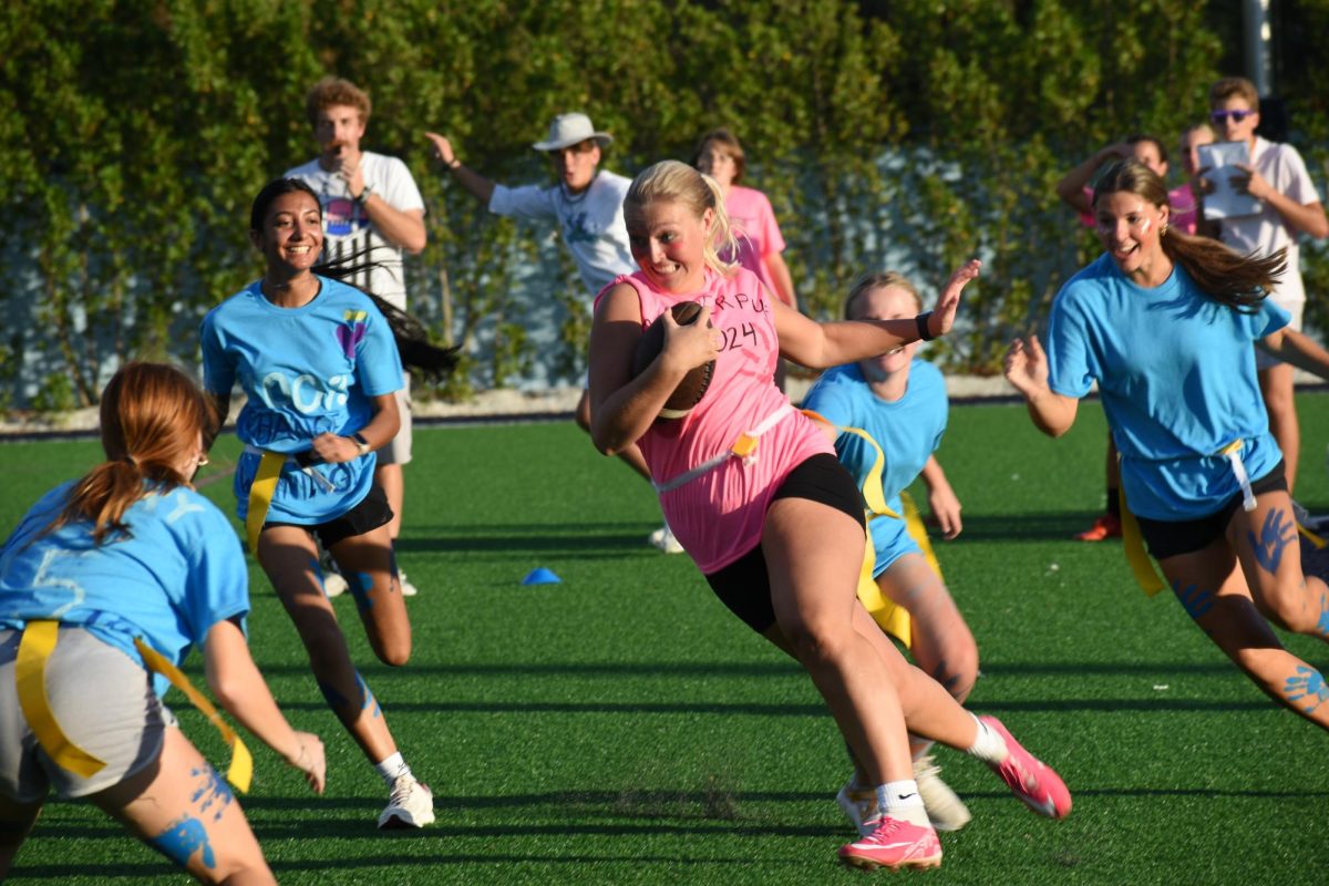 Lily Tessarzik getting the ball and running towards the end zone while dodging the blue team.