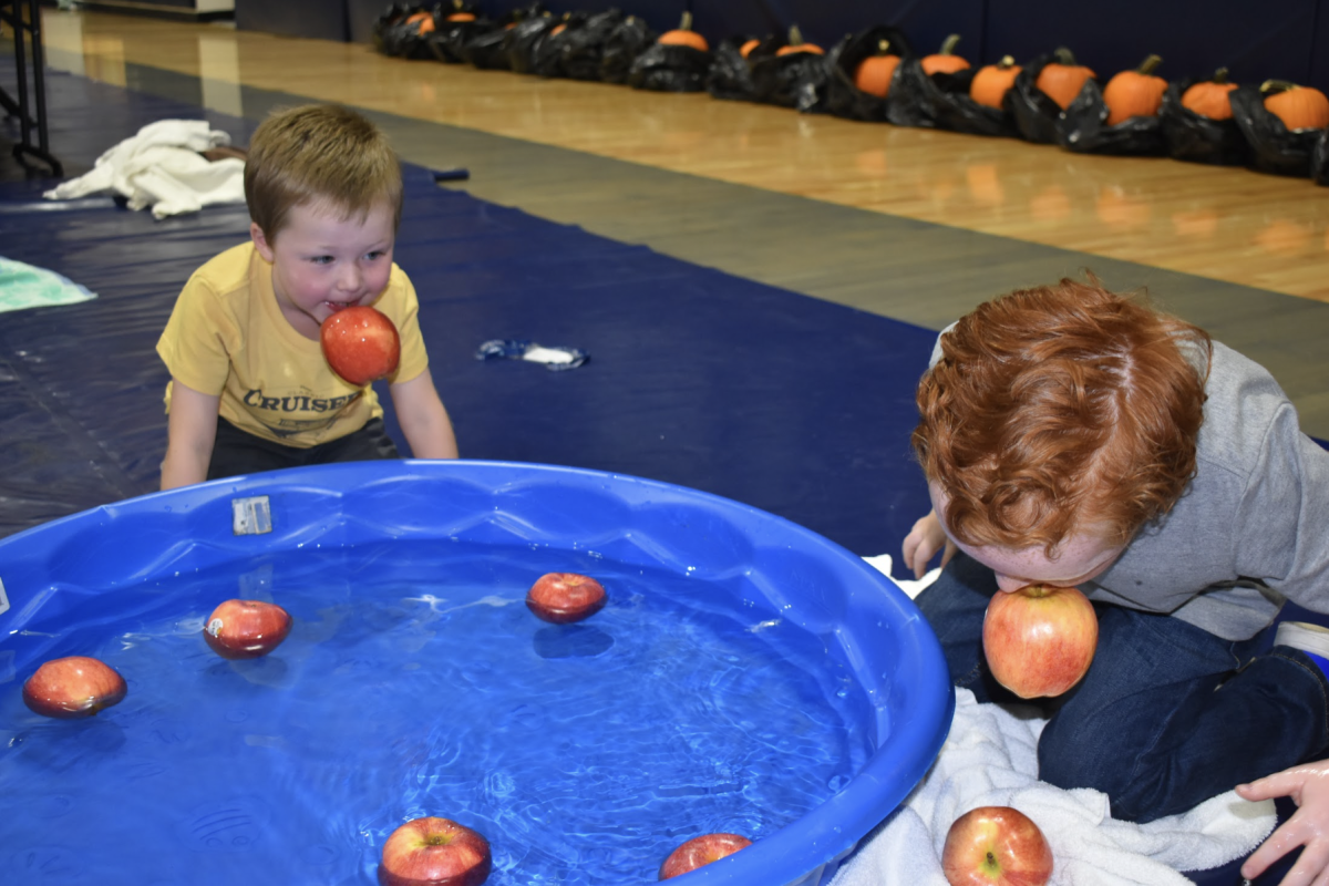 Two of the boys bobbing for apples while they are having the time of their lives.