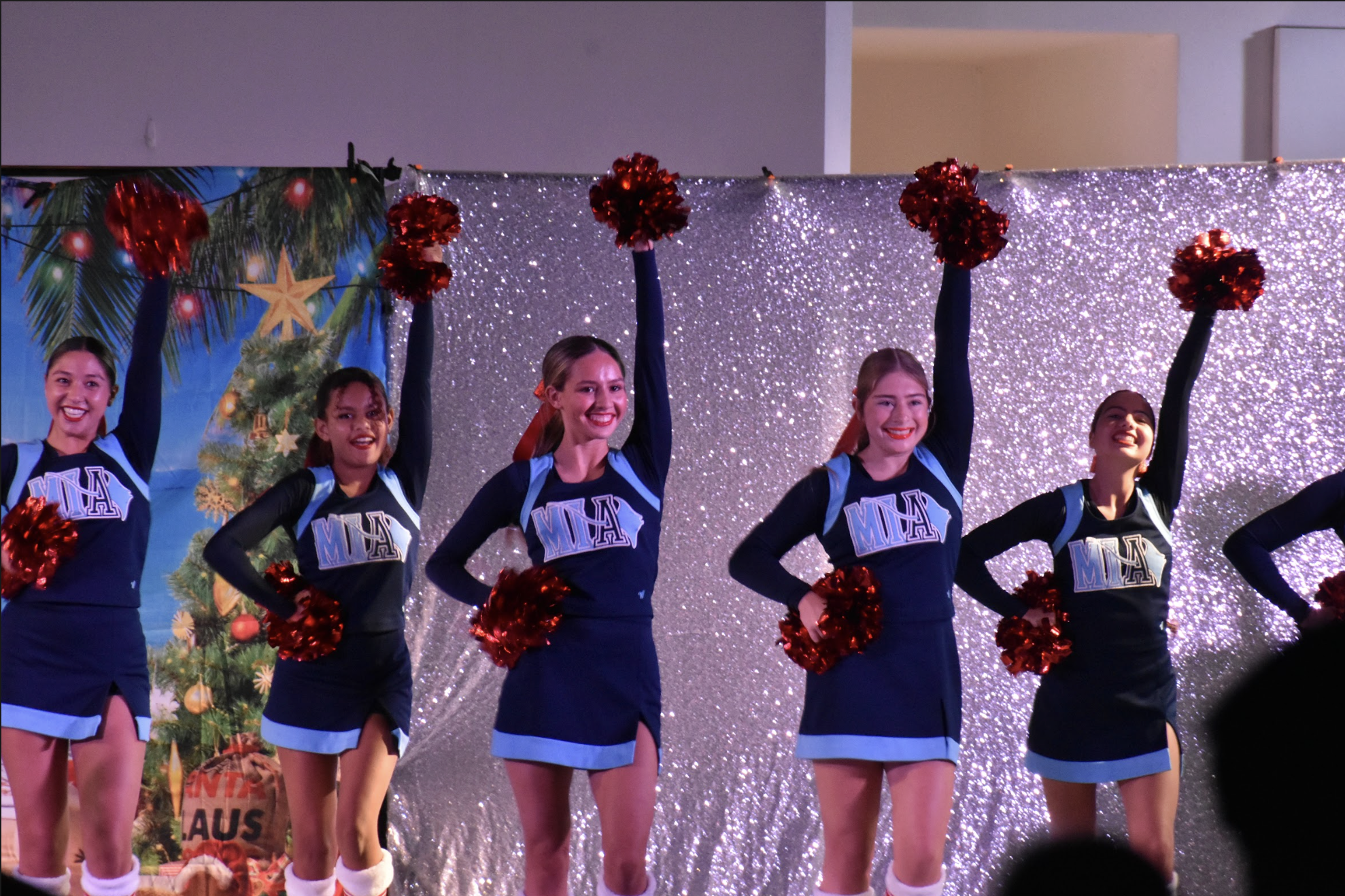 Cheerleaders hit a pose, smiling the crowd with Christmas cheer. 