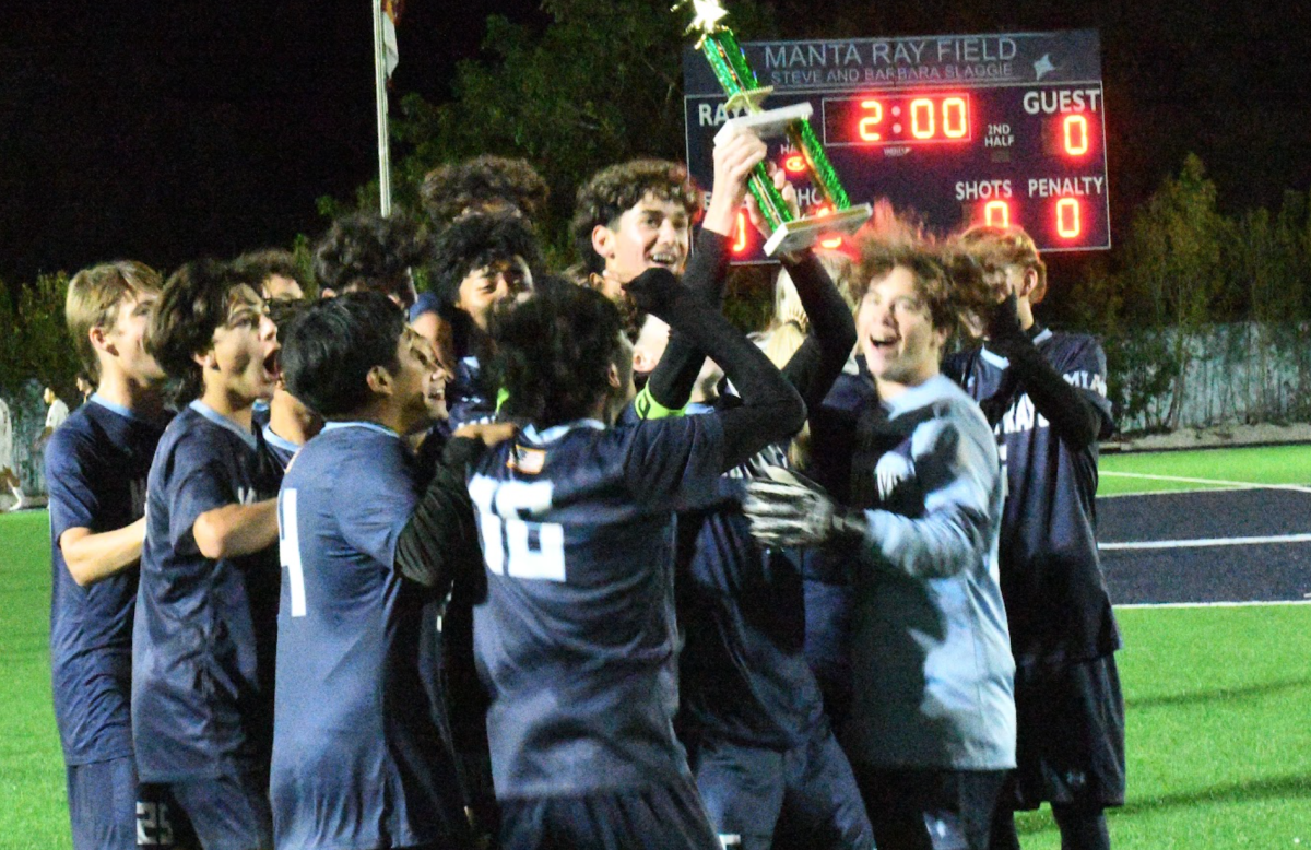The boys triumphantly holding the trophy in the air as they celebrate. 