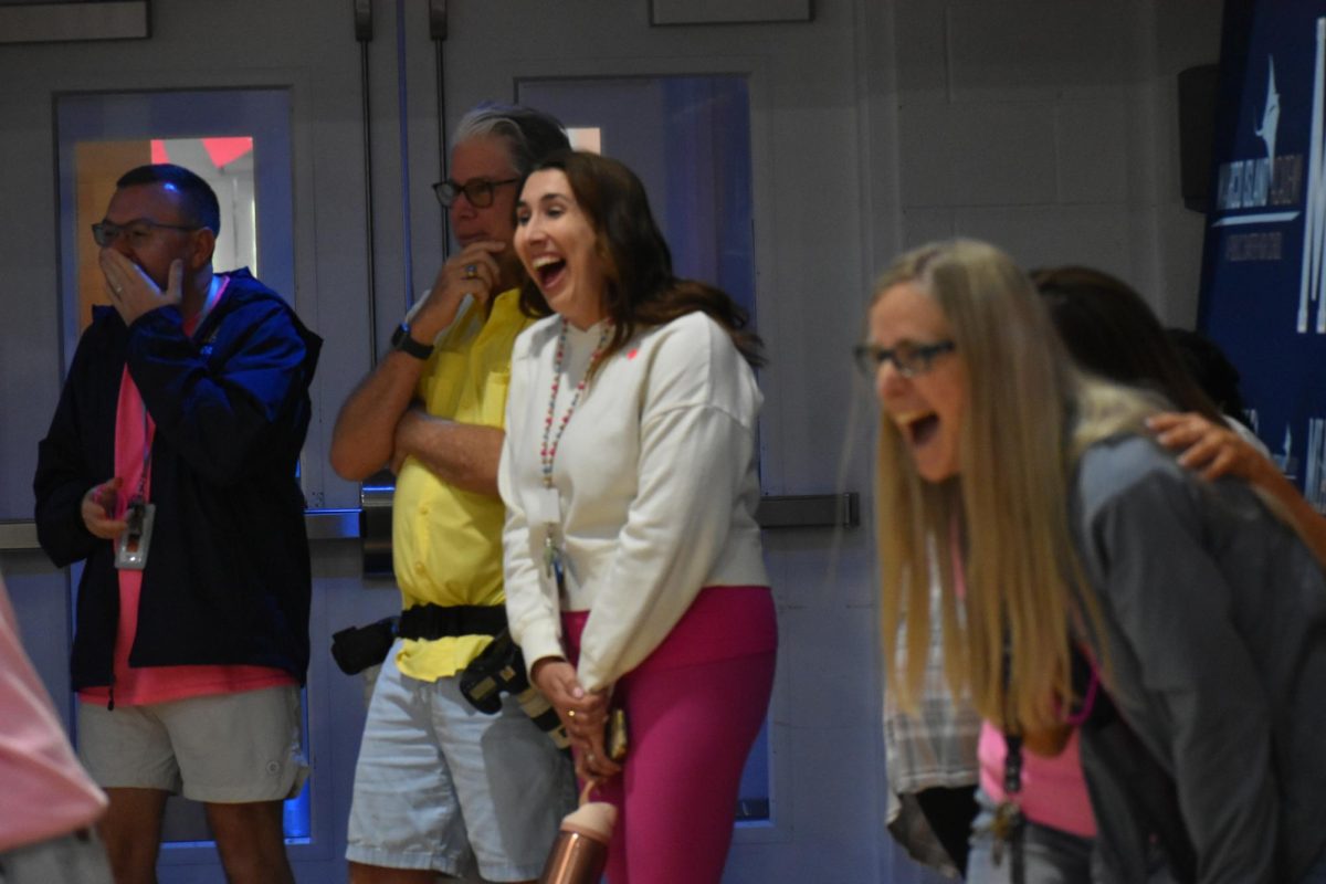 Staff laughing intensely, feeding off the pep rally’s fun energy.